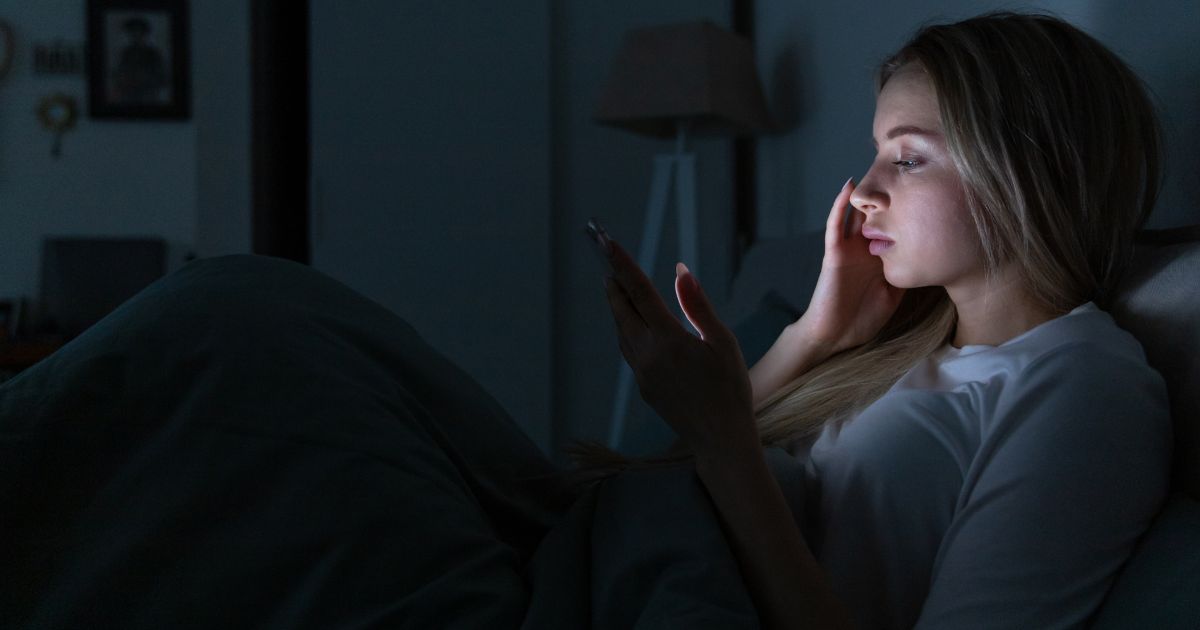 Woman Lying in Bed and Using Phone at Night